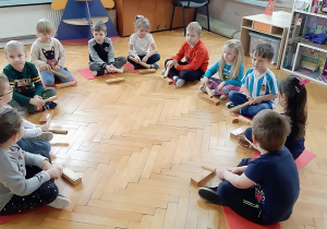 Dzieci wystukują rytm piosenki na drewnianych pudełkach.